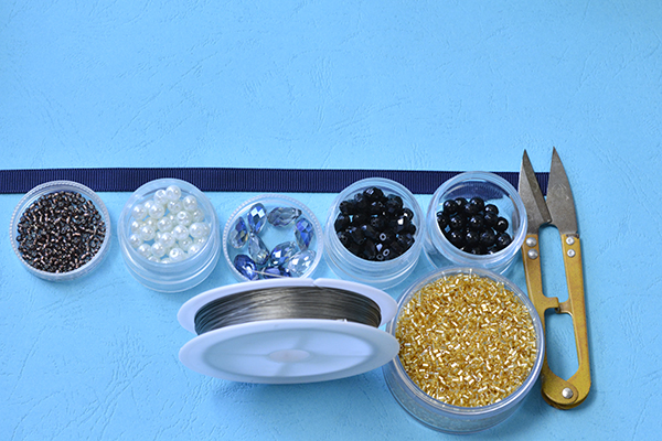 Supplies in making black and white beaded choker necklace with blue glass drops: