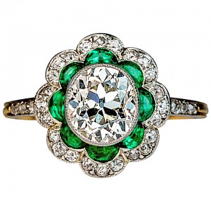 This 1920sl platinum and 18K gold ring with an approximately 1.50 ct oval diamond. Eight half-moon shaped emeralds look like petals in this floral design. Courtesy: 1stdibs.com