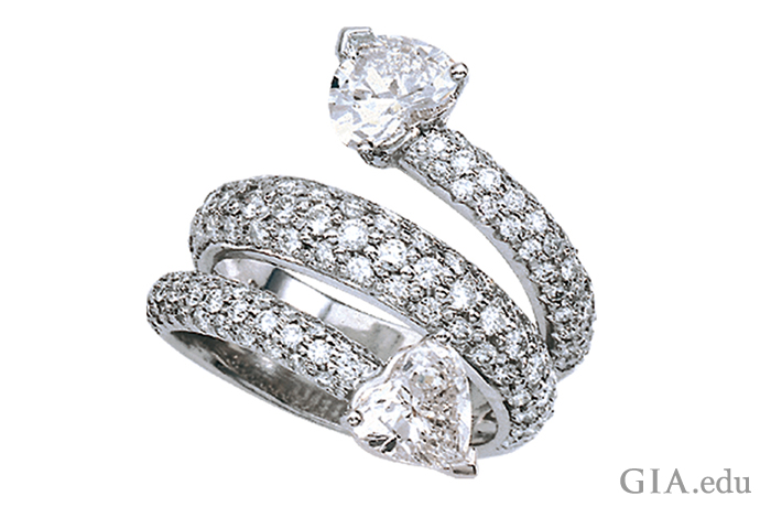 A Platinum ring with two heart-shaped diamonds joined by a coil of pavé-set diamonds. 
