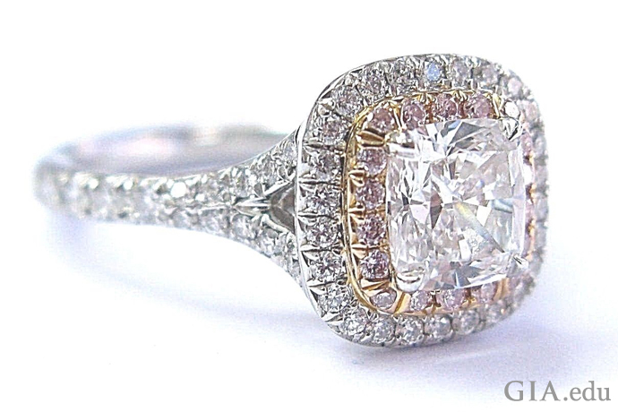 Cushion cut diamond and platinum engagement ring surrounded by a halo of melee and natural pink diamonds